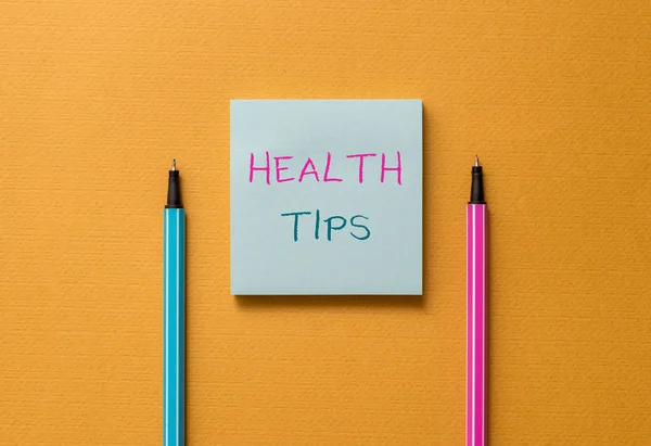 Tekstbord met tips voor de gezondheid. Conceptueel foto advies of informatie gegeven om behulpzaam te zijn bij gezond vooraanzicht blanco gekleurde Sticky Note twee Stylo cool dooier achtergrond. — Stockfoto