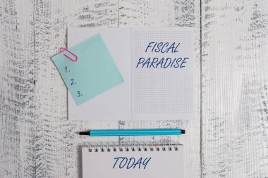 Word writing text Fiscal Paradise. Business concept for The waste of public money is a great concern topic Open squared spiral notepad clip note highlighter lying old wooden background. clipart