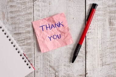 Teşekkür gösteren bir not yazmak. Bir hediye veya hizmet kabul ederken kullanılan kibar bir ifade vitrine İş fotoğrafı Kırışıklık kağıt defter ve ahşap arka plan üzerine yerleştirilmiş sabit.