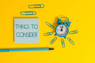 Word yazma metin Things Göz önünde bulundurulması gereken. Özellikle karar verirken dikkatlice düşünmek için iş konsepti Metal çalar saat uyandırma klipleri tükenmez not defteri renkli arka plan.