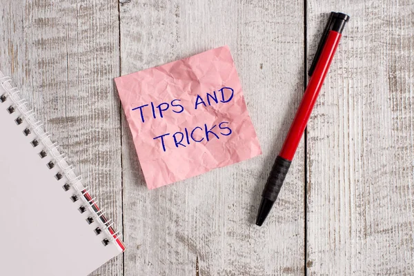 Writing note showing Tips And Tricks. Business photo showcasing piece of inside facts specially in betting or investing Wrinkle paper notebook and stationary placed on wooden background. — Stock Photo, Image