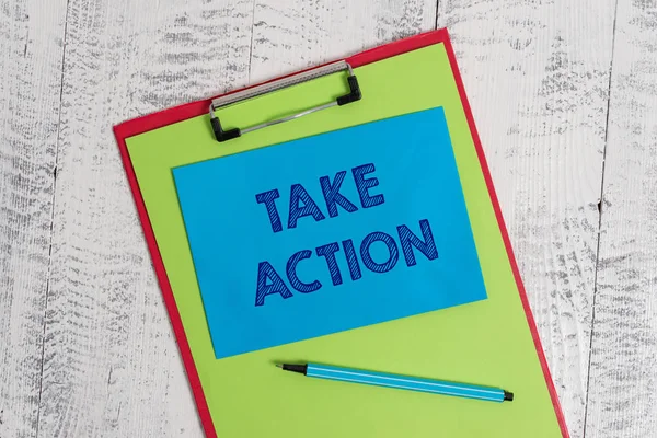 Text sign showing Take Action. Conceptual photo to do somethingoract in order to get a particular result Colored clipboard blank paper sheet marker sticky note wooden background.