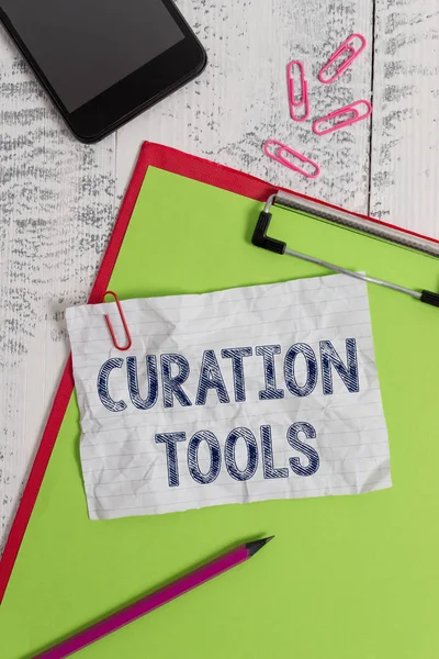 Handschrift tekst Curation tools. Concept betekenis software die wordt gebruikt bij het verzamelen van informatie die relevant is voor een onderwerp Klembord papier blad potlood smartphone Opmerking clips houten retro achtergrond. — Stockfoto