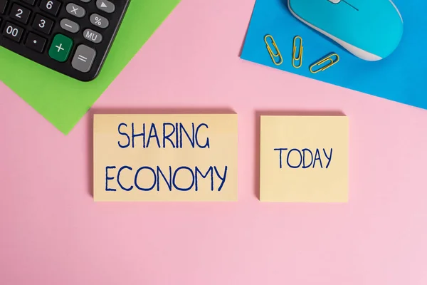 Writing note showing Sharing Economy. Business photo showcasing economic model based on providing access to goods Wire mouse portable calculator notepads paper sheets color background.