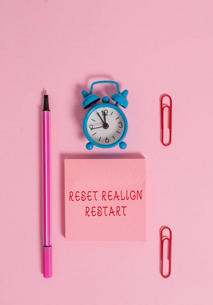 Conceptual hand writing showing Reset Realign Restart. Business photo text Life audit will help you put things in perspectives Metal alarm clock blank notepad marker clips colored background.