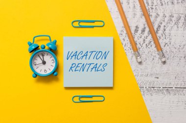 Text sign showing Vacation Rentals. Conceptual photo Renting out of apartment house condominium for a short stay Notepad clips colored paper sheet markers alarm clock wooden background. clipart