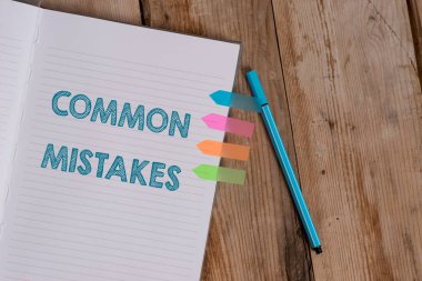 Conceptual hand writing showing Common Mistakes. Business photo text actions that are often used interchangeably with error Striped notebook colored arrow banners ballpoint wooden background. clipart