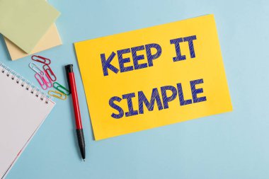 Keep It Simple'ı gösteren not yazma. İş fotoğraf vitrin bir şey anlamak kolay ve fantezi şekilde değil Düz karton ve pastel renk zemin üzerine yerleştirilen yazma ekipmanları.
