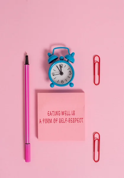 La escritura manual conceptual que muestra Comer bien es una forma de respeto a uno mismo. Texto de la foto de negocios una cita de promover un estilo de vida saludable Reloj despertador de metal bloc de notas clips marcador de color de fondo . —  Fotos de Stock