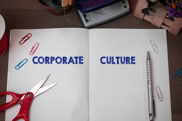 Writing note showing Corporate Culture. Business photo showcasing pervasive values and attitudes that characterize a company Scissors and writing equipments plus math book above textured backdrop.