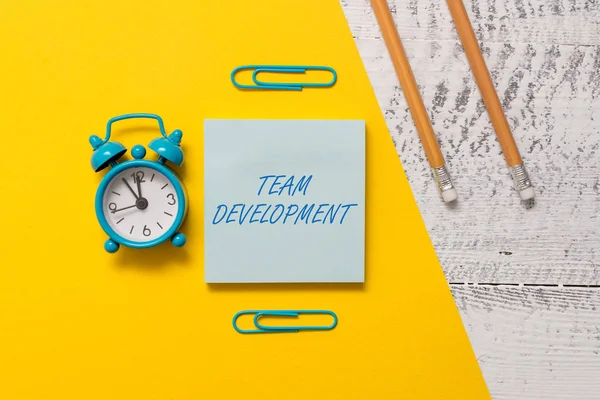 Text sign showing Team Development. Conceptual photo learn why and how small groups change over time with graphs Notepad clips colored paper sheet markers alarm clock wooden background. — Stock Photo, Image