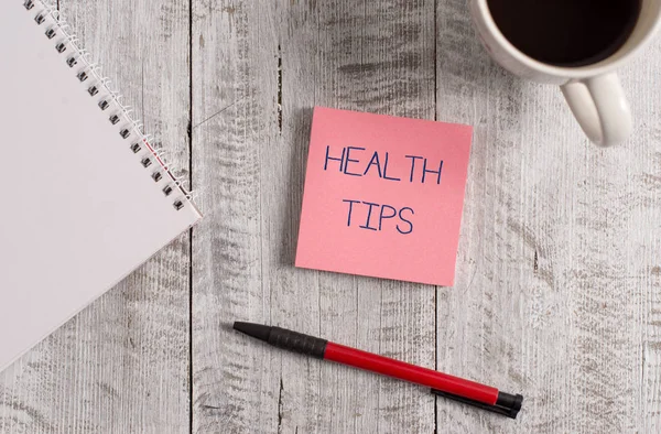 Texte manuscrit Conseils santé. Concept signifiant des conseils ou des informations donnés pour aider à être en bonne santé Stationnaire placé à côté d'une tasse de café noir au-dessus de la table en bois . — Photo