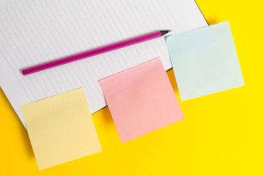 Kalemile sarı masada pembe boş kağıt. Düz metin mesajları için kopyalama alanı ile boş kağıtlar ile masanın üzerinde yatıyordu. Metin için boş kağıtlar ile iş kavramı.