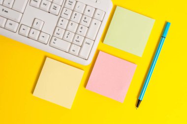 Sarı arka plan tablosu ve bilgisayar klavyesi üzerinde kopya alanı ile renkli boş kağıtlar. Metin mesajları için boş renkli kağıtlar ile turuncu tablo nun üzerinde düz yatıyordu.