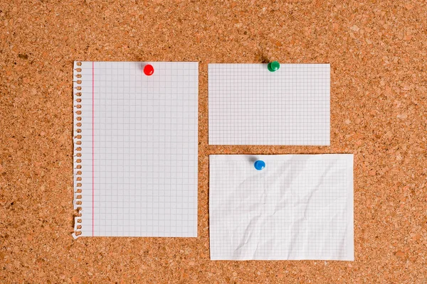 Corkboard with different color and size papers fixed by a pin. Rectangle and square shaped sheets stuck on a billboard by colored thumbtacks. Notice board with empty reminder note. — Stock Photo, Image