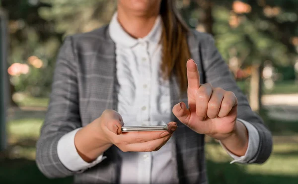 Mujer en suites grises tiene teléfono móvil. Concepto de negocio con mujer de negocios sosteniendo el teléfono móvil con pantalla táctil . —  Fotos de Stock