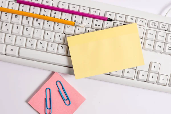 Clavier pc blanc avec papier de note vide et trombones au-dessus du fond blanc. Concept d'entreprise avec notes et clavier PC. Espace papier vierge pour message textuel . — Photo