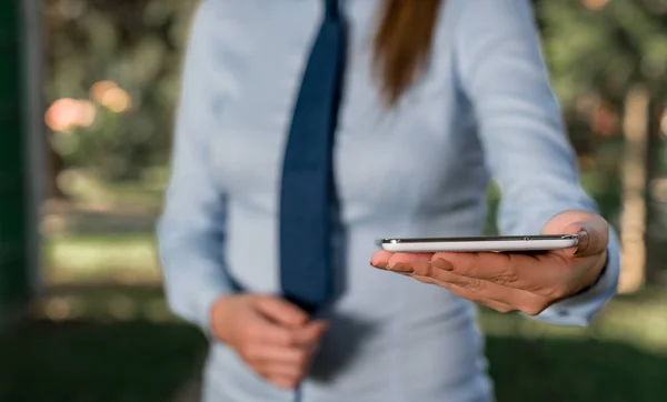 Affärskvinna i skjorta med en slips håller Lap Top mobiltelefon i handen. Kommunikationskoncept med mobiltelefon och affärskvinna. — Stockfoto