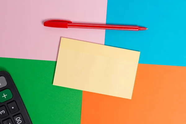 Escritorio colorido con diferentes tamaños y tipos de papeles vacíos, electrodomésticos de oficina y útiles de estudio. Mesa de papel cuadrado rosa, azul, verde y naranja con nota adhesiva . — Foto de Stock