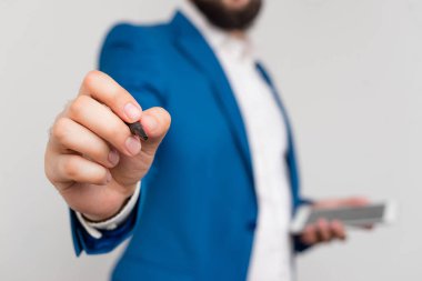 Önünde parmağını gösteren bir işadamı. İşadamı elinde tur üst tutar ve parmağıyla puan.