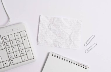 Beyaz arkaplanın üzerinde boş not kağıdı olan beyaz pc klavyesi. Not ve klavyeli iş konsepti. Metin iletisi için boş kağıt alanı.
