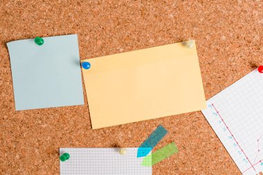 Mantar pano farklı renk ve boyutta kağıtlarla iğne ile sabitlenmiş. Reklam panosuna renkli raptiyelerle yapıştırılmış dikdörtgen ve kare şekilli çarşaflar. Boş hatırlatma notlu bildirim tahtası.