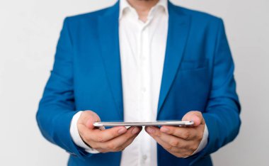 Mavi süitve beyaz gömlekli adam elinde cep telefonu tutuyor. Elinde işadamı ve cep telefonu ile iş konsepti.