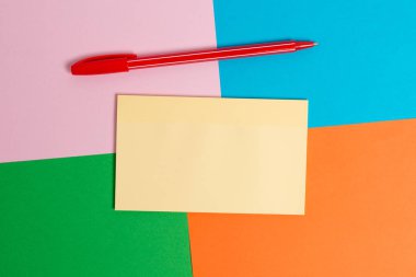 Farklı boyutlarda ve boş kağıtlar, ofis aletleri ve çalışma malzemeleri türleri ile renkli masa. Tablo etiket notu ile pembe, mavi, yeşil ve turuncu kareler kağıt tan yapılmış.