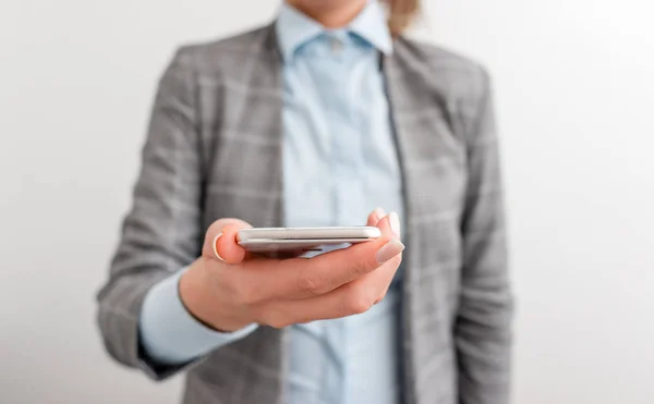 Femme d'affaires tient le téléphone portable dans la main. Concept d'entreprise avec téléphone portable et femme d'affaires. Belle femme dans une suite d'affaires avec téléphone . — Photo