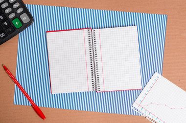 Çizgili mavi kağıtlı karton masa, defter kağıdı ve ofis aletleri. Farklı boyutlarda ve tipte kağıtları olan karton masa, rakamlarla ve çalışma malzemeleriyle dolu bir tablo..