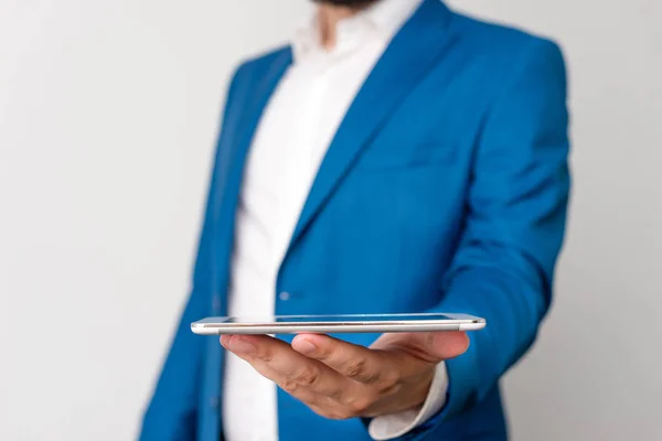 Homem na suíte azul e camisa branca segura telefone celular na mão. Conceito de negócio com homem de negócios e telefone celular na mão . — Fotografia de Stock