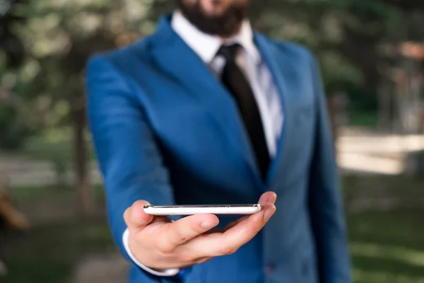 Affärsidé med man som håller mobiltelefon med pekskärm. Affärsmannen håller Lap Top i handen. Affärsman i Blue Suite står med mobiltelefon i händerna. — Stockfoto