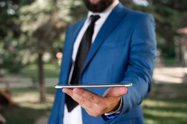 Affärsidé med man som håller mobiltelefon med pekskärm. Affärsmannen håller Lap Top i handen. Affärsman i Blue Suite står med mobiltelefon i händerna. — Stockfoto