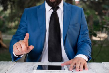 Önünde parmağını gösteren bir işadamı. İşadamı elinde tur üst tutar ve parmağıyla puan.