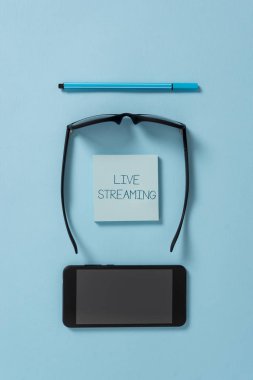 Canlı Akış'ı gösteren metin işareti. Kavramsal fotoğraf İnternet üzerinden bir olayın canlı video kapsama aktarın Karanlık gözlük renkli yapışkan not akıllı telefon kalem serin pastel arka plan.