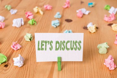 Conceptual hand writing showing Let S Discuss. Business photo showcasing asking someone to talk about something with demonstrating or showing Colored crumpled papers wooden floor background clothespin clipart