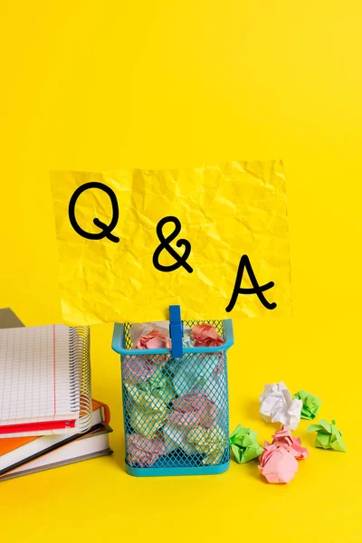 Conceptual hand writing showing Q And A. Business photo showcasing defined as questions being asked and answers Trash bin crumpled paper clothespin office supplies yellow.