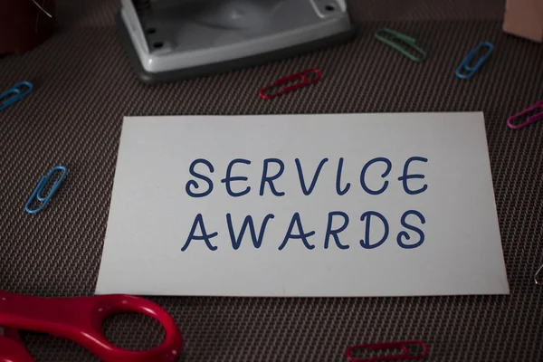 Word writing text Service Awards. Business concept for Recognizing an employee for his or her longevity or tenure Scissors and writing equipments plus plain sheet above textured backdrop.