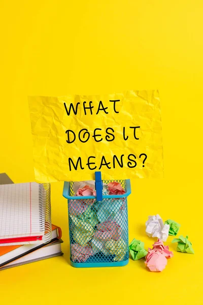 Conceptual hand writing showing What Does It Means question. Business photo showcasing asking someone about meaning something said and you do not understand Trash bin crumpled paper clothespin office