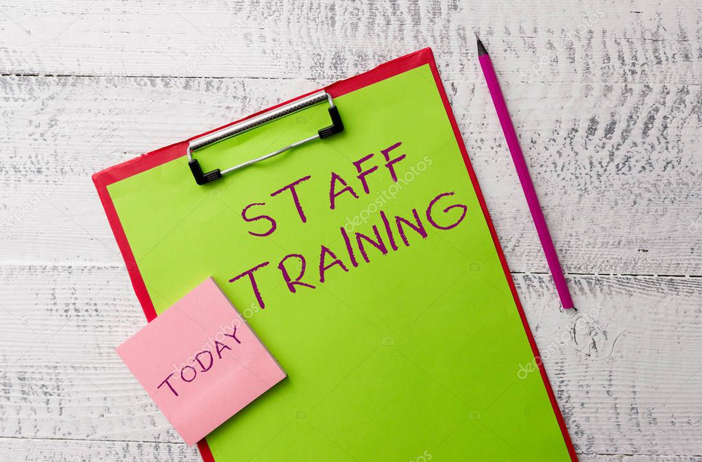 Word writing text Staff Training. Business concept for A program that helps employees to learn specific knowledge Metal clipboard paper sheets marker sticky notes pad wooden background.