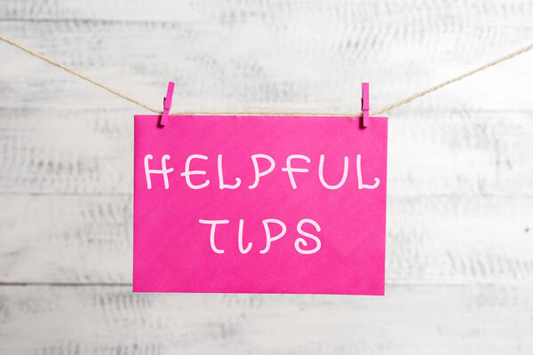 Word writing text Helpful Tips. Business concept for advices given to be helpful knowledge in life Clothesline clothespin rectangle shaped paper reminder white wood desk.