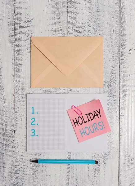 Writing note showing Holiday Hours. Business photo showcasing Overtime work on for employees under flexible work schedules Envelop squared notepad note clip marker old wooden vintage background.