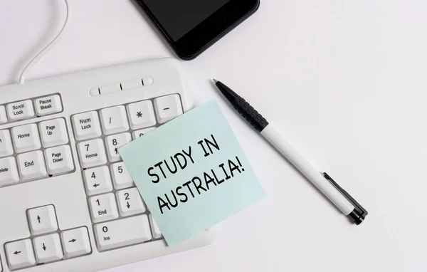 Handwriting text writing Study In Australia. Concept meaning going into foreign country order complete your studies White pc keyboard with empty note paper above white background. — Stock Photo, Image