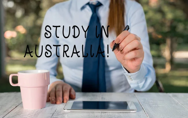 Nota de redação mostrando Study In Australia. Foto de negócios mostrando indo para a ordem do país estrangeiro completar seus estudos Feminino empresário sentado à mesa e segurando o telefone móvel . — Fotografia de Stock