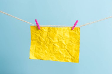 Dikdörtgen şeklinde not renkli kağıt beyaz ahşap arka planda clothespin tarafından bir çamaşır ipi kırpılmış. Kare boş hatırlatma ve ofis ekipmanları malzemeleri hafif ahşap bir masada.