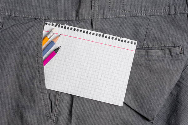 Writing equipment and a white note paper inside the formal working trousers front pocket. Stationary pencil with notation sheet placed in man work pants