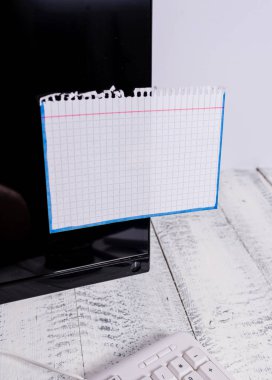 Notasyon kağıdı, tahta masanın üzerindeki beyaz klavyenin yanındaki siyah bilgisayar ekranına yapışır. Üzerine bantlanmış beyaz not yaprağı ile qwerty yakın yerleştirilen PC monitör.