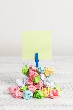 Mavi bir çamaşır iğnesi ile sabitlenmiş buruşuk kağıtları bir yığın yukarıda Kare şeklinde hatırlatma. Boş renkli bir notun altına yığılmış farklı yapraklar. Beyaz ahşap zemin ve beyaz arka plan.