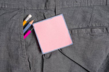 Resmi çalışma pantolonu ön cebinde ekipman ve pembe bir not kağıt yazma. Erkek iş pantolonuna yerleştirilen notasyon kağıdı ile sabit kalem