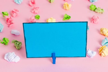 Pembe arka planda boş dikdörtgen kare şeklinde hatırlatma notu etrafında yerleştirilen renkli buruşuk levhalar. Ofis malzemeleri, bir bağlantı elemanı tarafından sabitlenmiş boş kağıt.